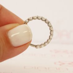 a hand holding a diamond ring in front of a white background