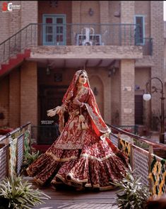 a woman in a red and gold bridal gown is walking down the stairs outside