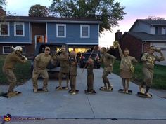 several statues of soldiers are posed on skateboards in front of a house at dusk