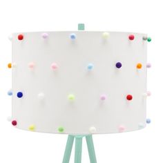 a white lamp with multicolored dots on the fabric shade and wooden legs, against a white background