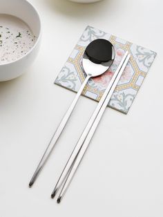 two silver spoons sitting on top of a white table