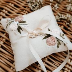 a ring pillow with flowers on it sitting in a wicker basket