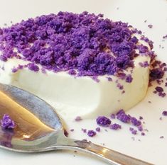 there is a piece of cake with purple sprinkles on it next to a spoon