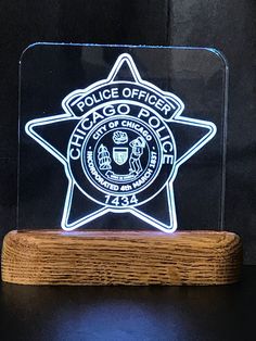 an illuminated police officer badge on a wooden base with a black background and white lettering