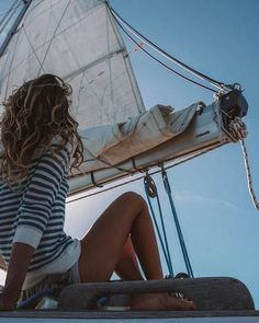 a woman sitting on top of a sail boat