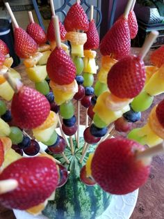 fruit skewers are arranged in the shape of watermelon, strawberries and grapes