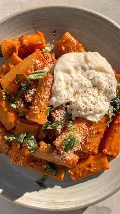 a white bowl filled with pasta covered in sauce and parmesan cheese on top