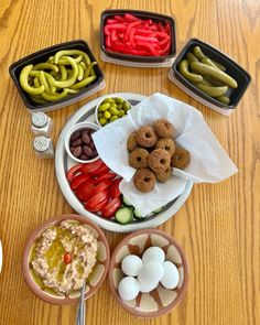 a table topped with bowls filled with different types of food next to containers of pickles