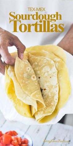 a person is holding up some tortillas on a plate with tomatoes and salsa