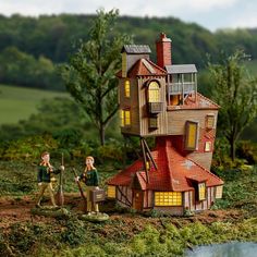 two figurines are standing in front of a doll house with a pond and trees