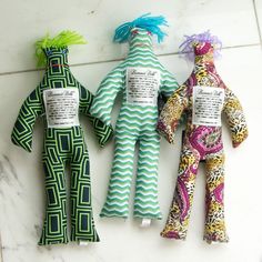 three colorful stuffed animals sitting next to each other on a white counter top with labels