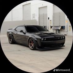 a black sports car parked in front of a building with its hood up and wheels down