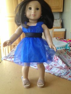 the doll is wearing a blue dress and sandals