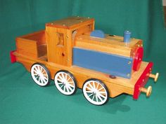 a wooden toy train is shown on a green background with white wheels and red rims