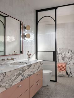 a bathroom with marble counter tops and pink cabinets