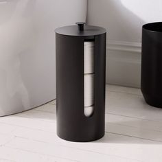 a black trash can sitting on top of a white floor