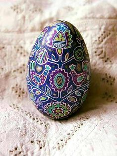 an egg painted with colorful designs sitting on a bed