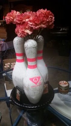 three bowling pins with flowers in them sitting on a table