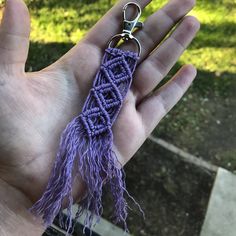 a hand holding a purple keychain with a knot on it