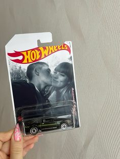 a hot wheels car is being held up to the camera by a woman's hand