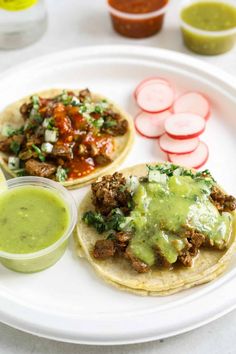 two tacos on a plate with sauce and vegetables