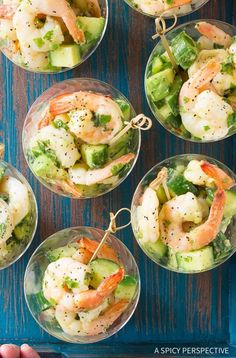 shrimp and cucumber salad in small glass bowls on a blue tray with two hands