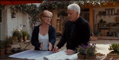 an older man and woman looking at plans on a table