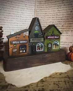 two wooden houses are sitting on top of a piece of paper next to some pumpkins