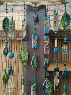 green and blue beads are hanging from a bamboo structure with leaves on it, along with other decorative items