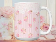 a pink and white coffee mug sitting on top of a wooden table next to flowers