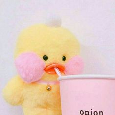 a yellow stuffed animal holding a pink cup with a straw in it's mouth