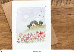 a card with watercolor flowers and a house on the hill