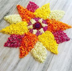 colorful flower petals laid out on top of a wooden table with white and yellow flowers