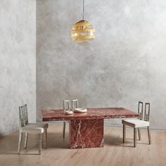 a marble dining table with two chairs and a pendant light hanging from the ceiling over it