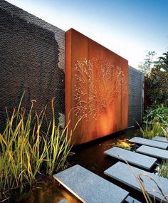 an outdoor water feature in the middle of a garden with stepping stones and plants on it