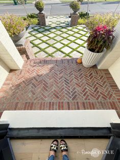 a person standing on top of a brick floor next to a planter filled with flowers