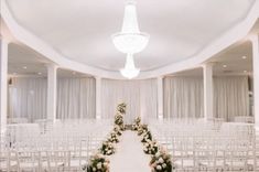 an empty room with rows of white chairs and flowers on the back of each chair