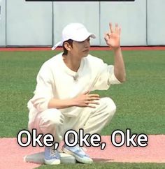 a man sitting on top of a baseball field holding his hand up in the air