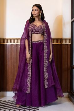 Sparkling grape purple cape with floral jaal embroidered border. Paired with an inner padded blouse with all over golden floral jaal work in zari, cutdana, and sequins. Comes along with a sharara. Components: 3 Pattern: Embroidery Type Of Work: Floral, Cutdana, Sequins Neckline: Blouse: Sweetheart Neck Sleeve Type: Cape: Split Sleeves Fabric: Organza Color: Purple Other Details:  Model Height: 5ft 7inches, wearing size S Length: Sharara: 43 inches Blouse: 14 inches Padded bodice Attached inner l Sangeet Sharara Outfits, Purple Cape Dress, Shurgs Designs Dress, Sharara Models, Sharara With Jacket, Blouse Sweetheart Neck, Cape Sharara, Purple Cape