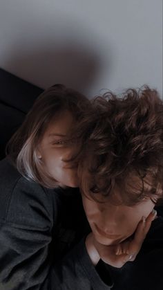 a young man with curly hair laying on top of a bed