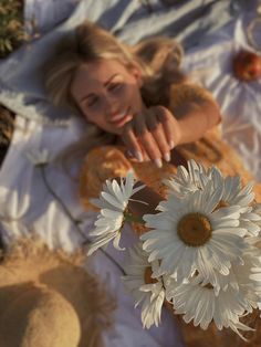 a woman laying on the ground next to two white flowers