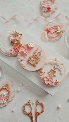 some pink and gold buttons are laying on a white surface next to other crafting supplies