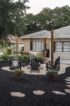 an outdoor patio with chairs and lights on the roof, surrounded by black mulch