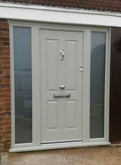 a white double door in front of a brick building with glass panels on the side