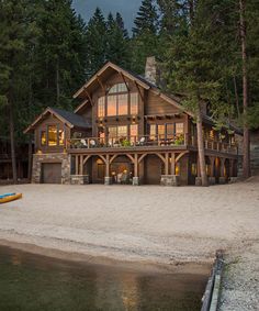 a large house sitting on top of a sandy beach next to a forest covered hillside