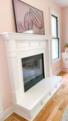 a living room with pink walls and a white fireplace