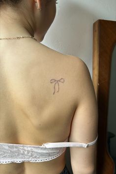 womens back of shoulder blade handpoked tattooed of a ribbon bow very small with black and grey ink handpoked fresh light pink lacey bra gold necklace and earrings Small Bow Tattoo, Dragon Tattoo Ideas, Aesthetic Tattoos, Small Pretty Tattoos, Bow Tattoo, Petite Tattoos