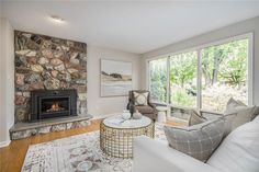 a living room filled with furniture and a fire place in front of a stone wall