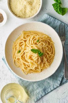 a white bowl filled with pasta and parmesan on top of a blue towel