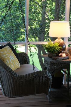 a chair and table on a porch with a lamp in the corner next to it